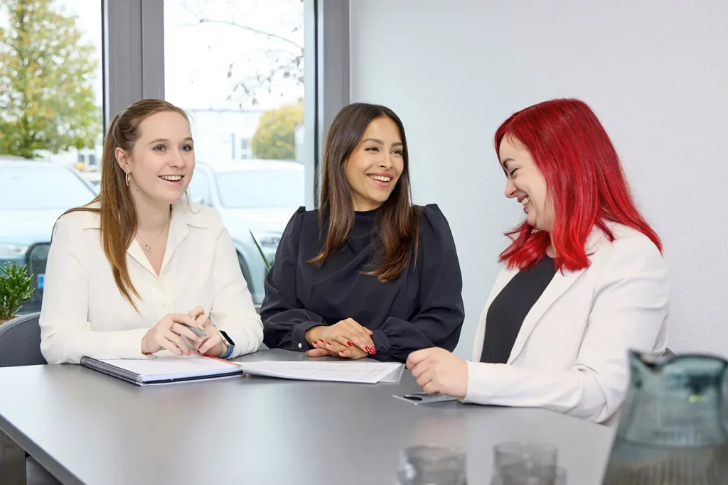 Rebecca, Beste und Denise sitzen im Besprechungsraum und unterhalten sich